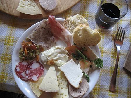 A rich plate with selection of cheese and many other local specialties