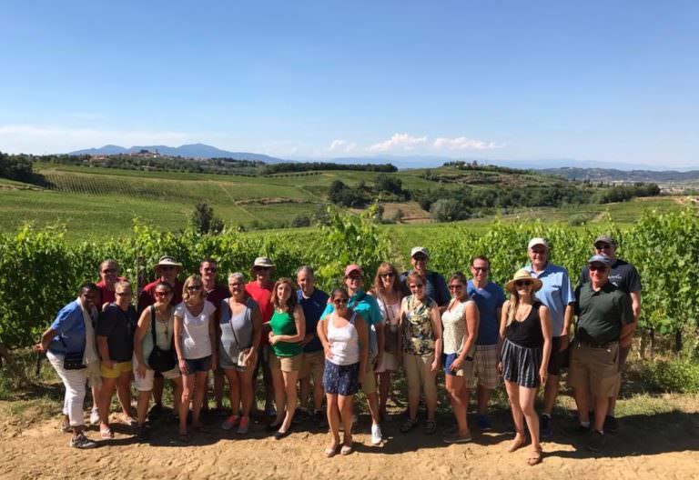 Small group posing in front of a stunning sangiovese vineyard